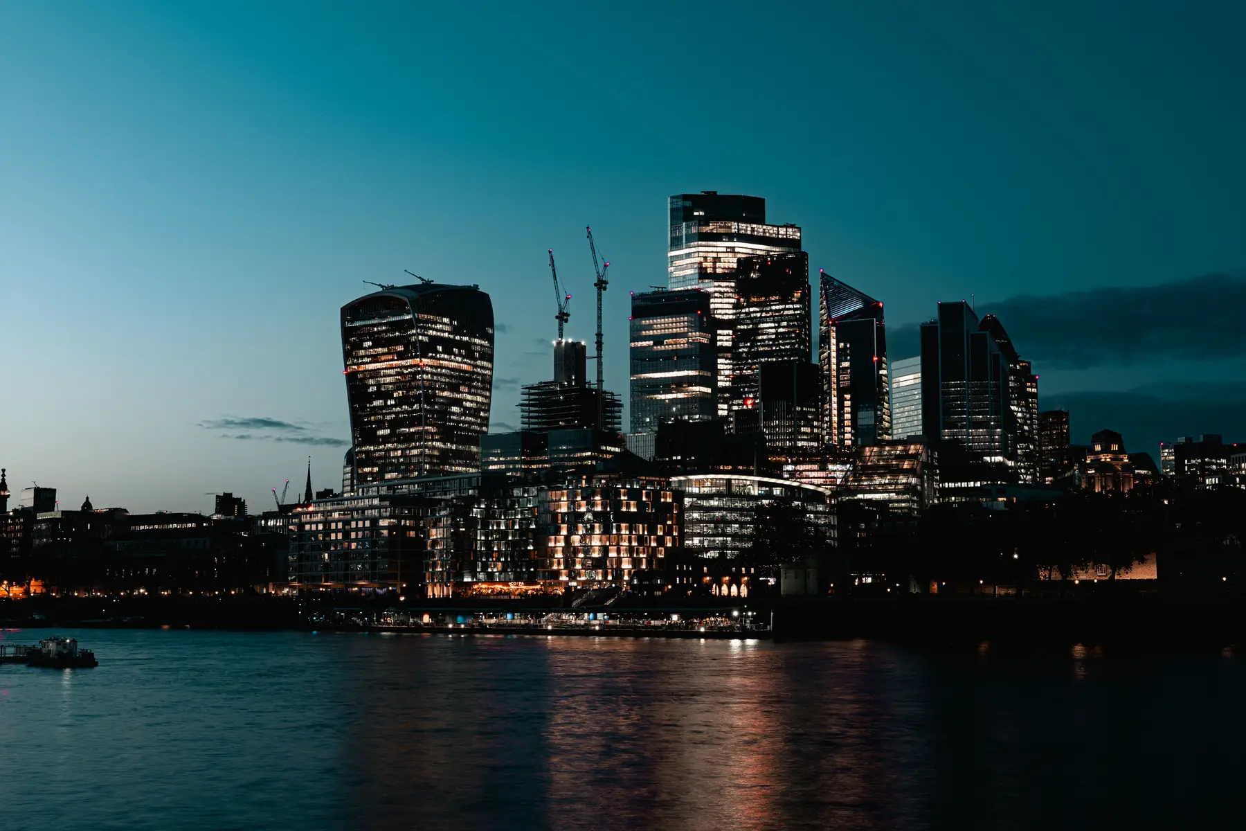 The City of London skyline at dusk, reflected in the Thames
