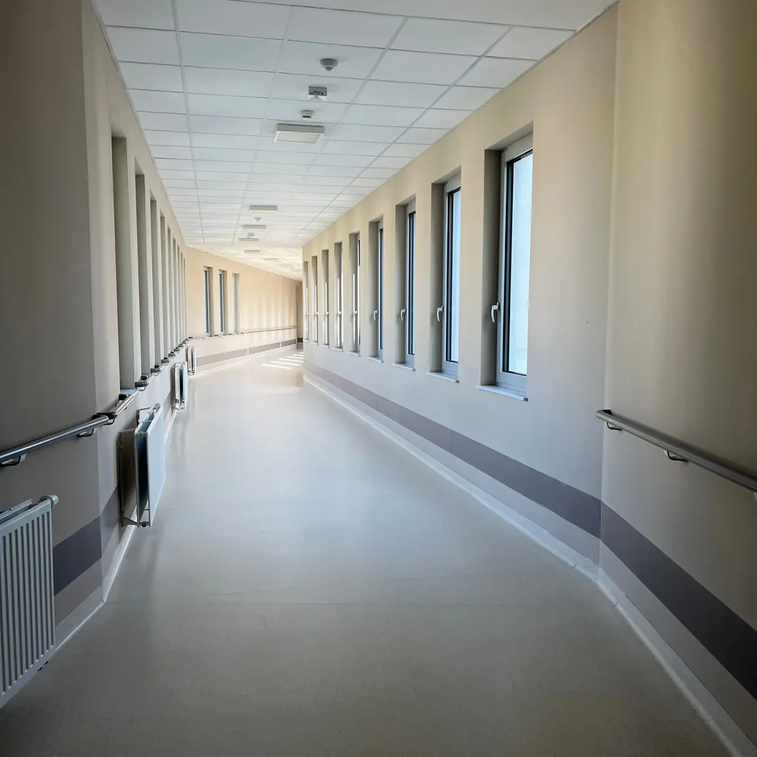 A bright hospital corridor with tall windows